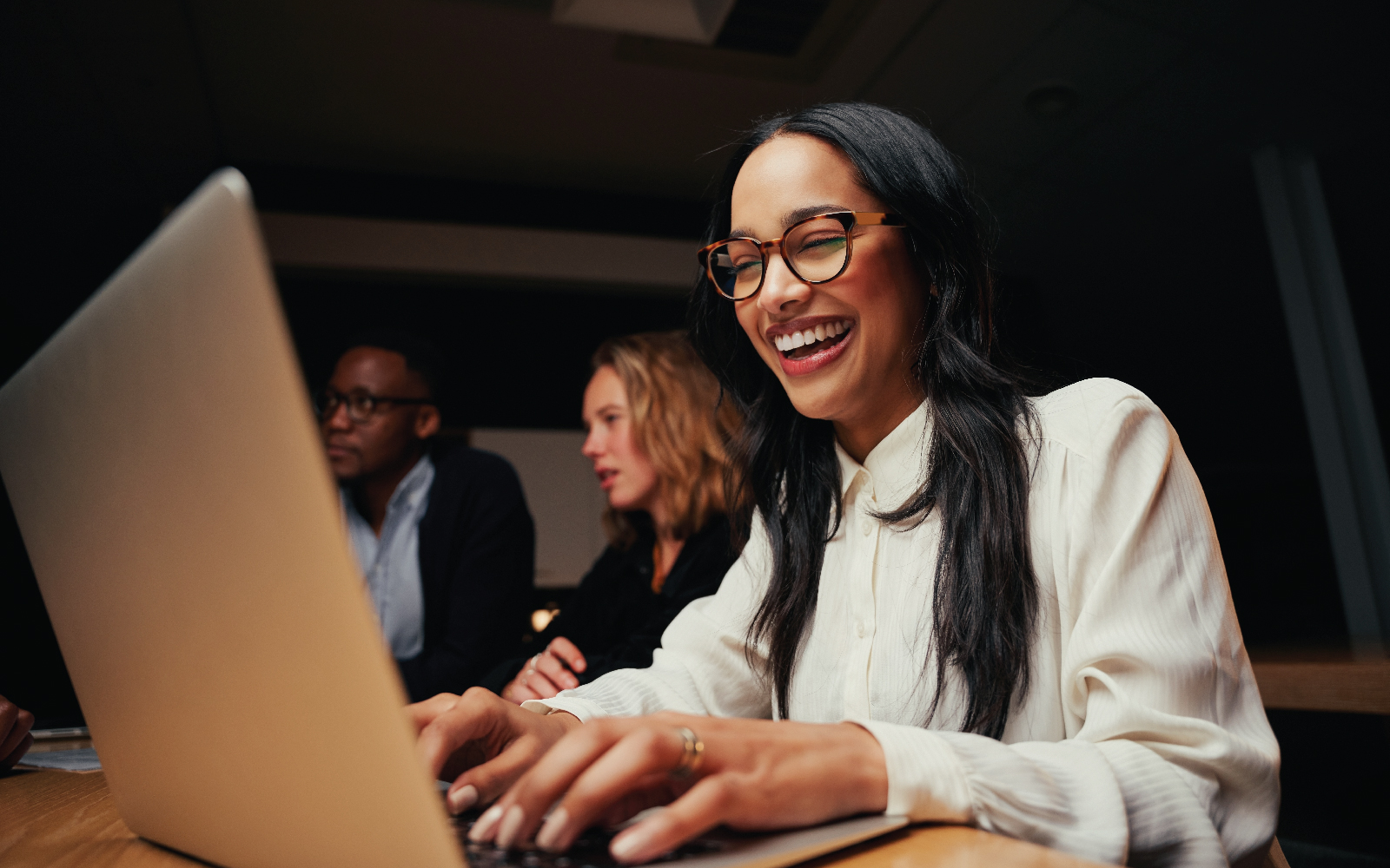 Girl with glasses smiling at laptop