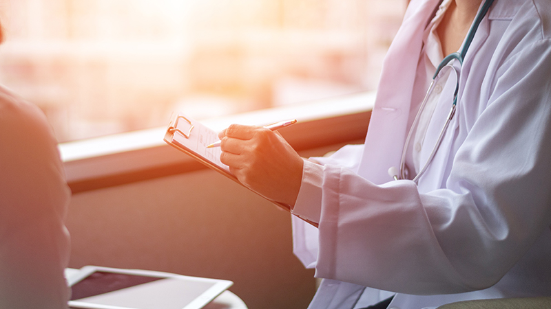Close up of a doctor writing on a clipboard