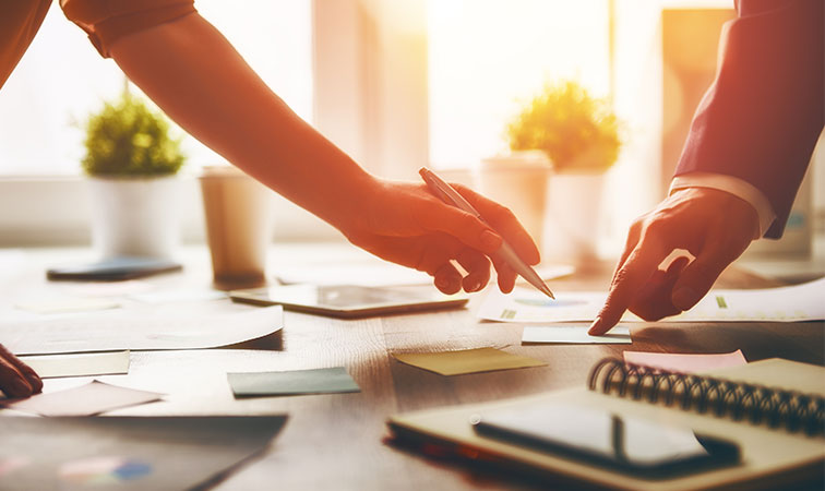 Two business people analyzing documents on table
