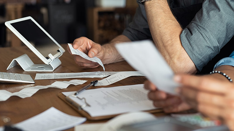 People reviewing documents at table with clipboard and tablet