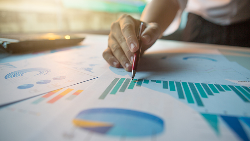Close up of a hand writing on printed graphs with a pen